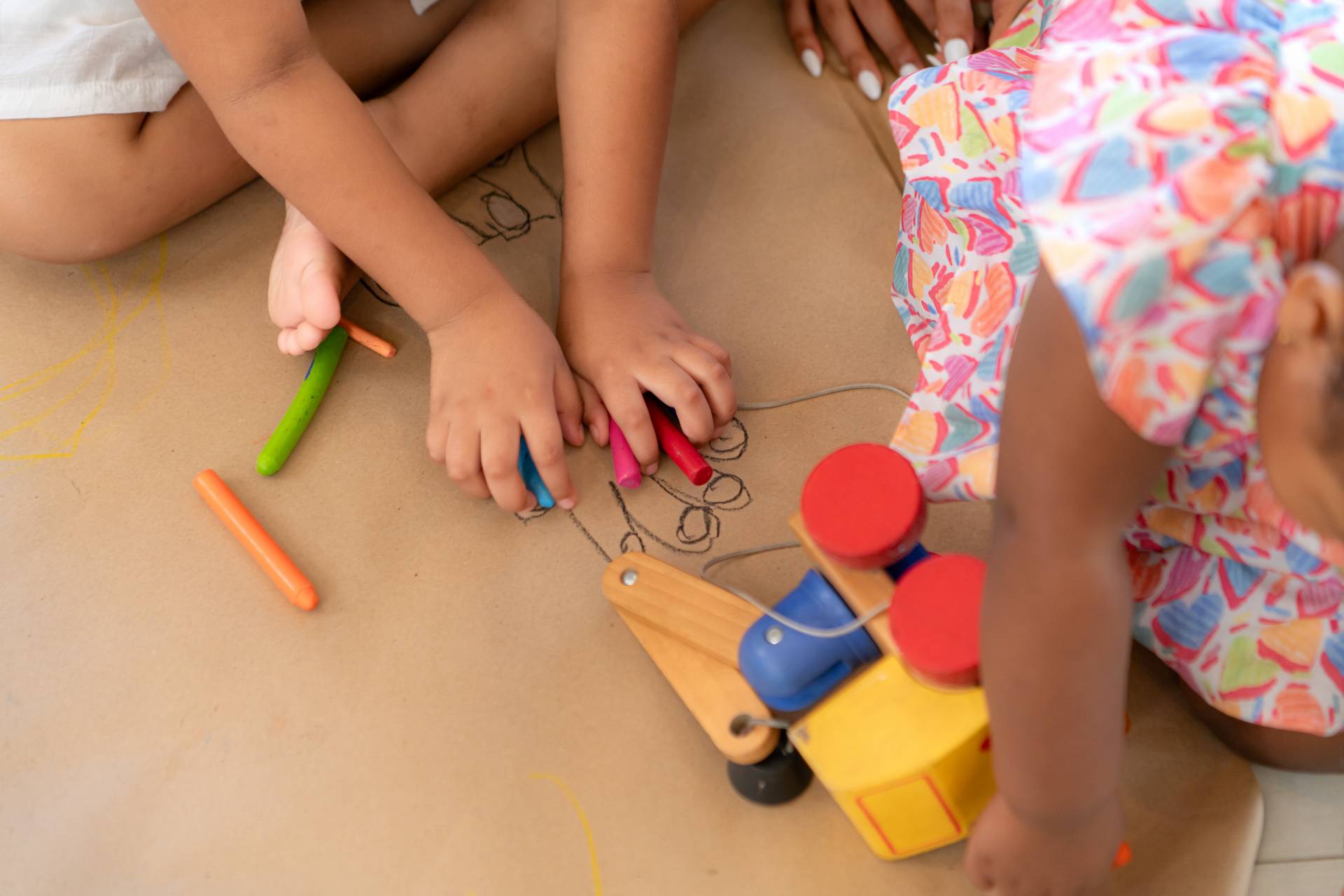 On a holiday, A woman and her two little daughters sit on the floor and drawing together in the living room